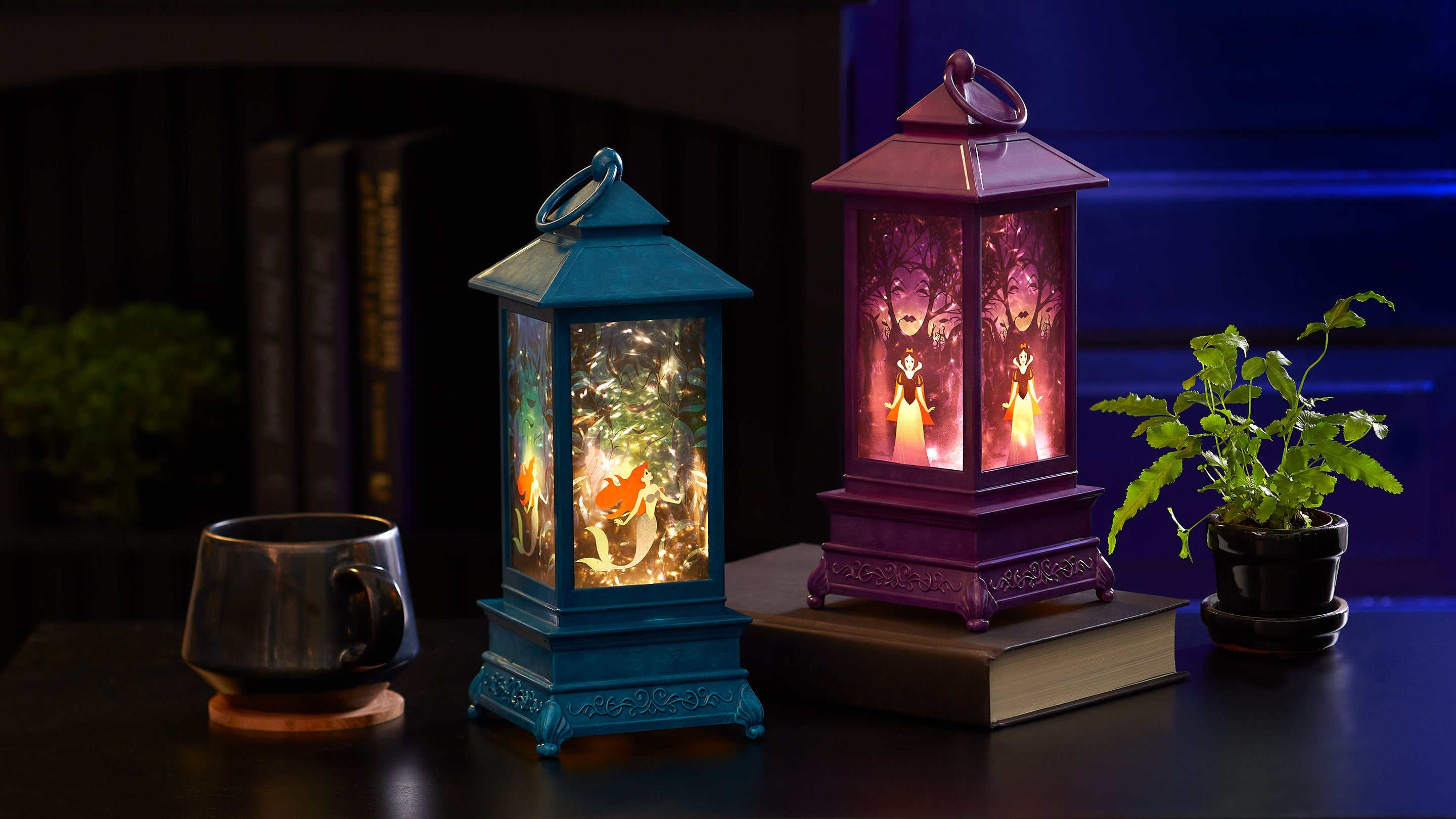 Two colorful lanterns with decorative figures inside on a dark surface.