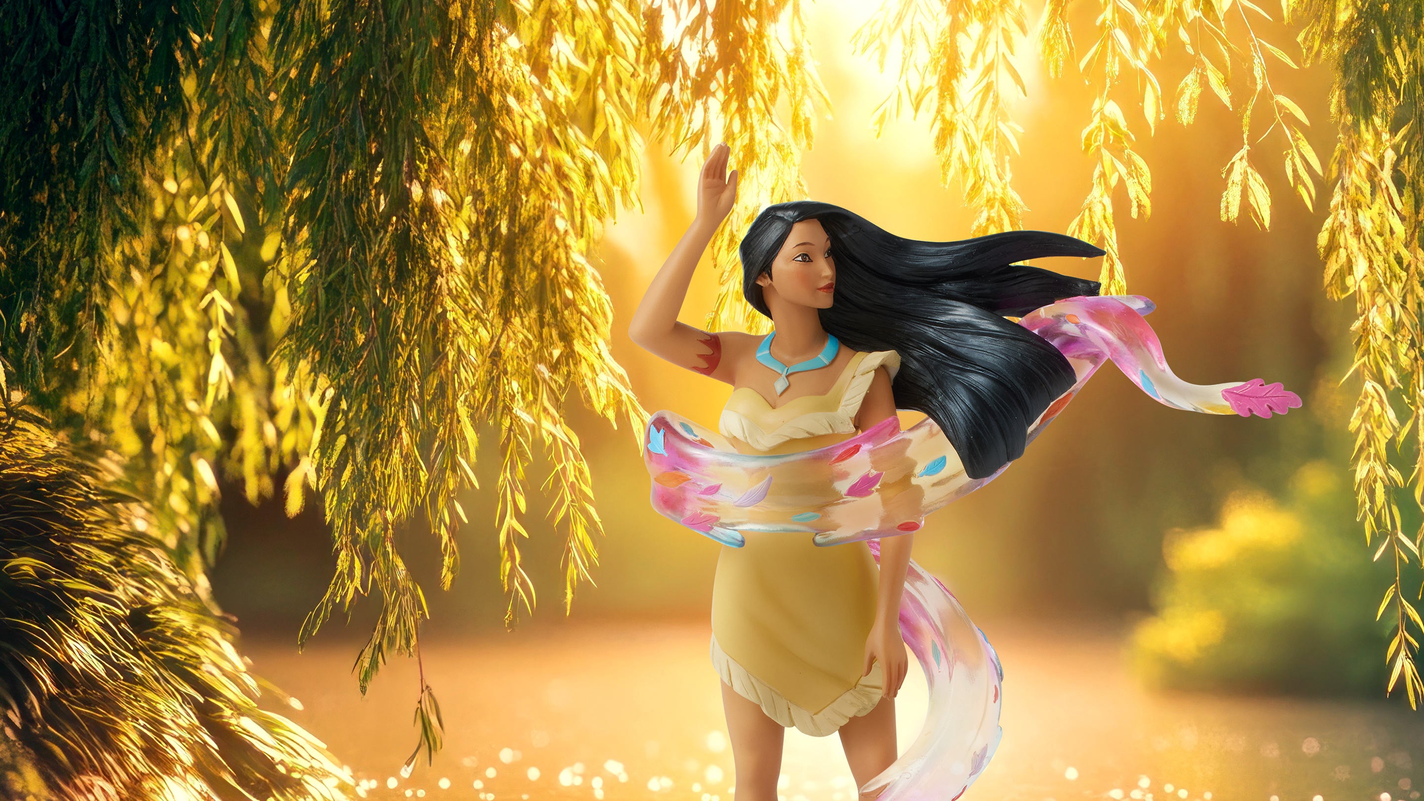 Figurine of a woman in a yellow dress with flowing hair and colorful scarf, standing under a willow tree with a warm glow.