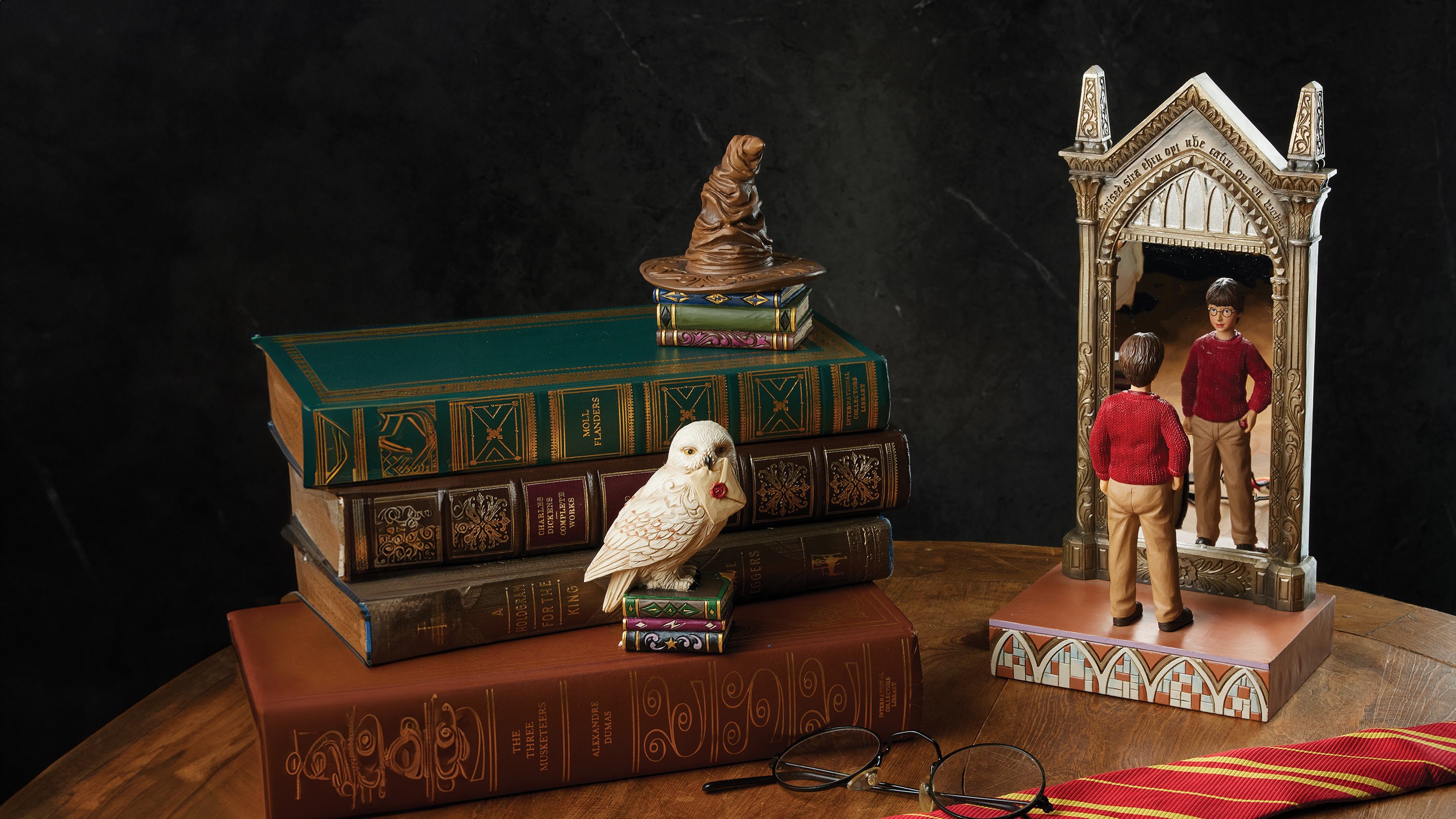 Decorative set with books, a dog figurine, a bird, and a mirror on a dark background