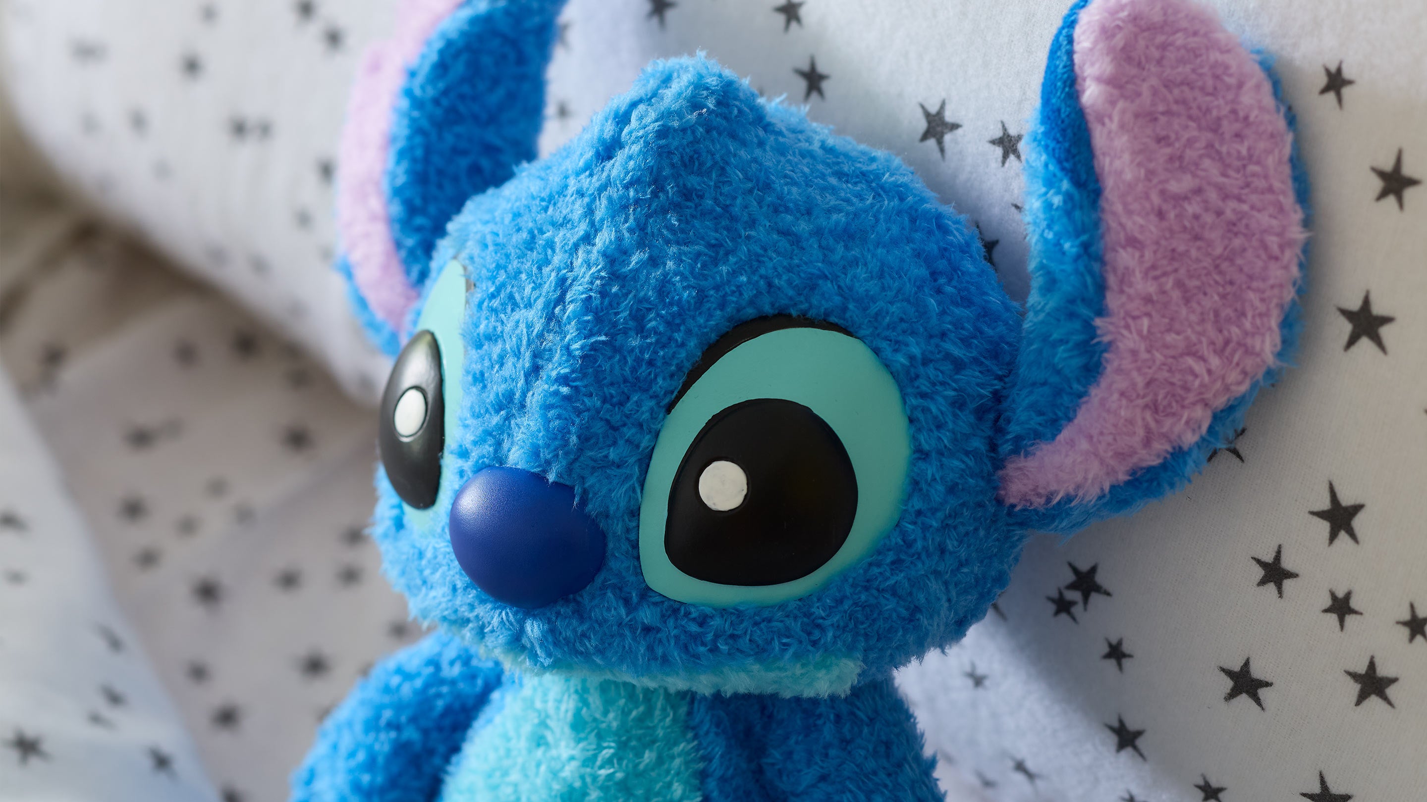 Blue plush toy with pink inner ears on a white background with black star patterns