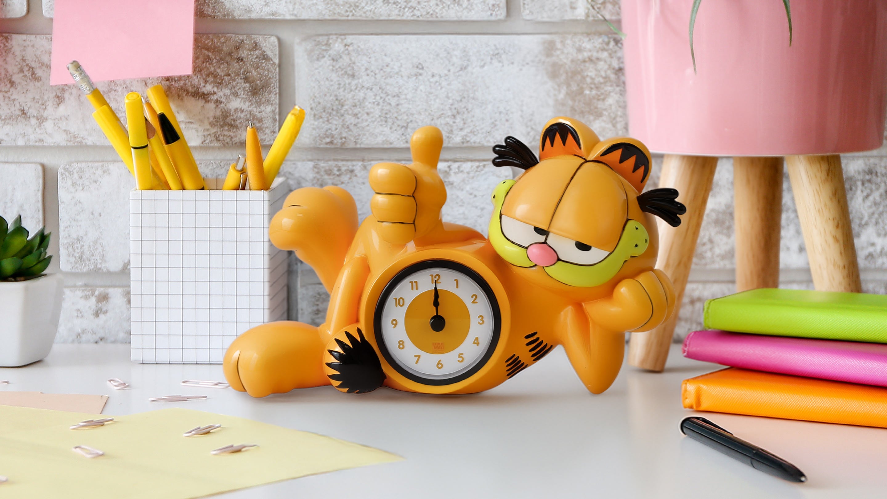 Garfield-themed alarm clock on a desk with stationery items