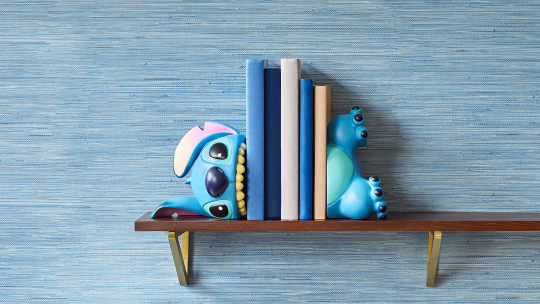 Decorative bookends shaped like cartoon characters on a shelf against a blue striped wall.
